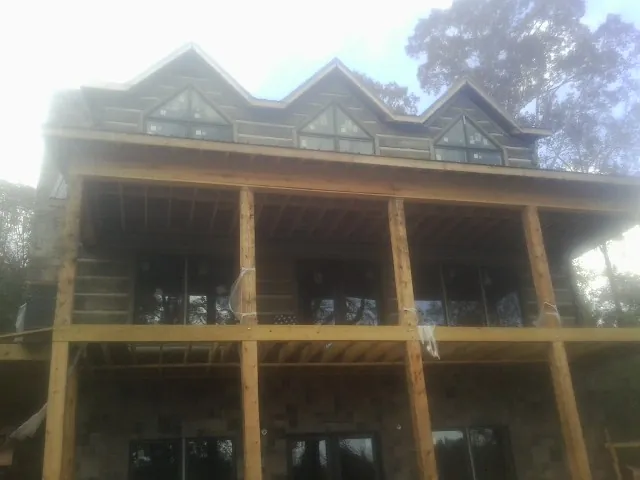 Dormers and porch framing on a large log home under construction — Roof Coating work by our crew in Kenmare