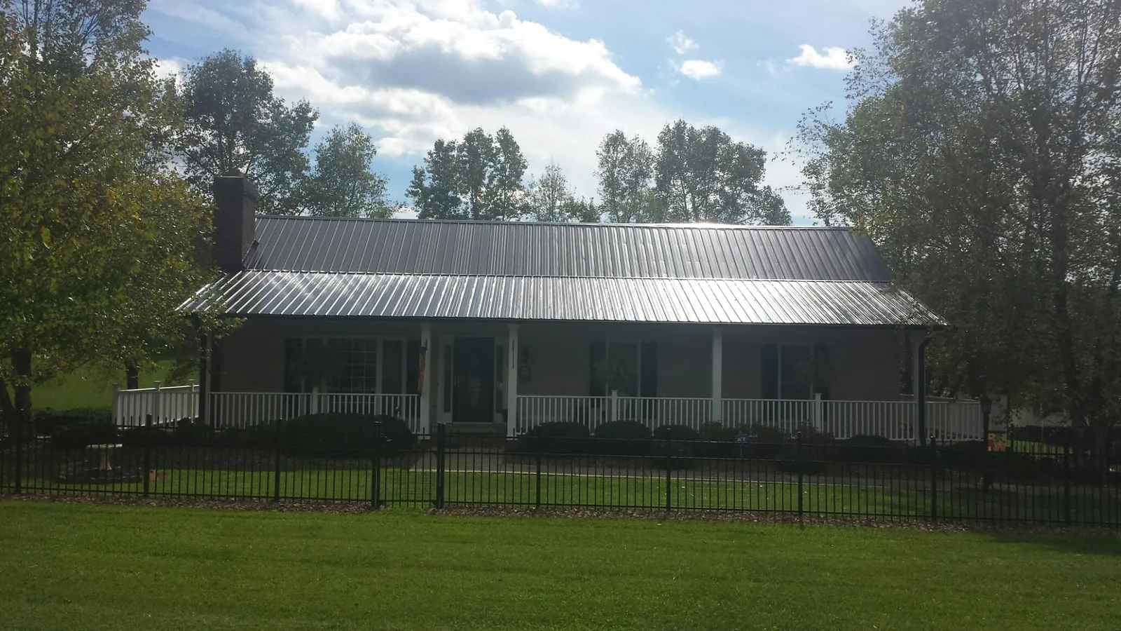 Gray metal roof on a brick ranch with a full width front porch — Gutter Guard Installation work by our crew in Kenmare