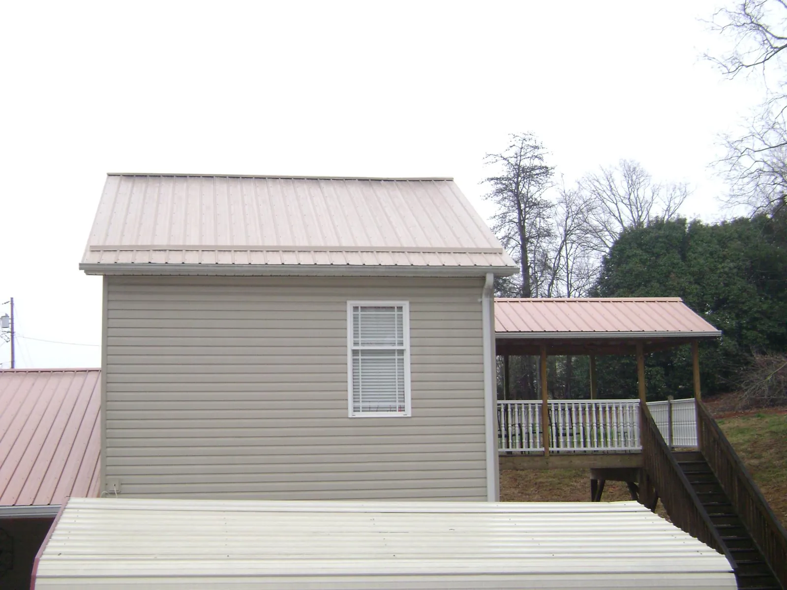 Tan metal roofs on a two story addition and attached porch, from a Roof Replacement job in Kenmare